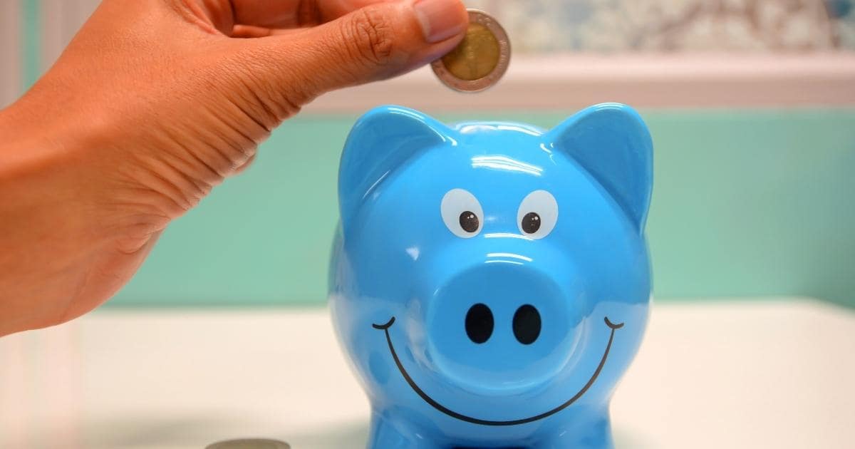 blue piggy bank and hand dropping coin