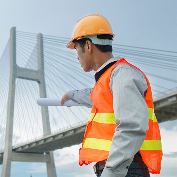 Man with construction uniform looks out to bridge