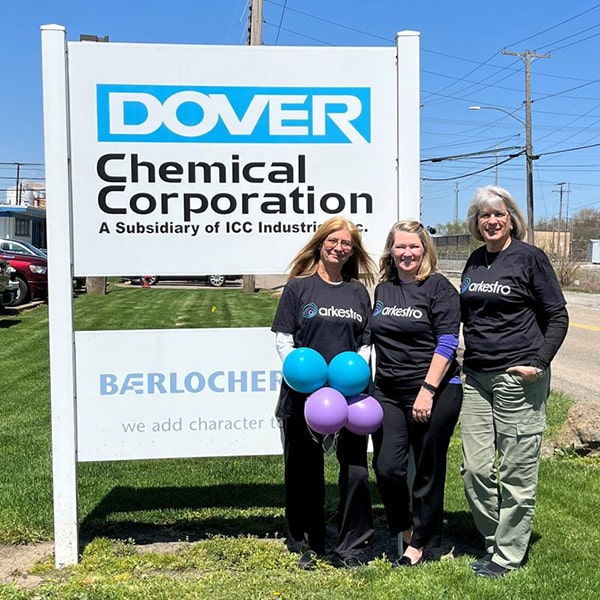 Three people standing by a Dover Chemical sign