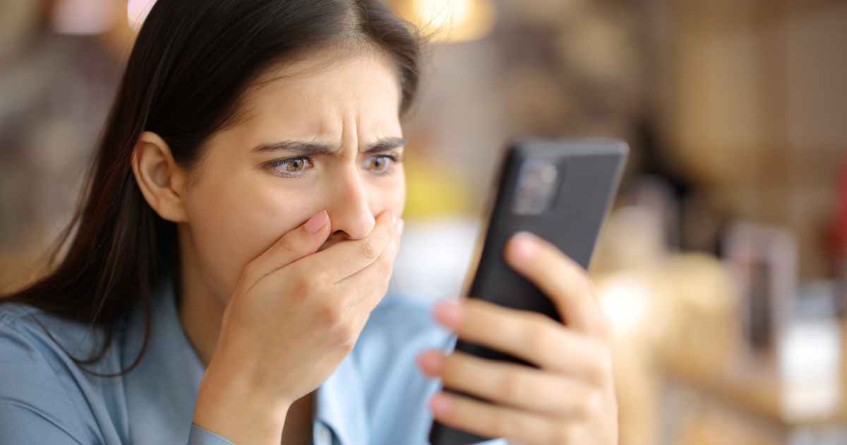 woman looking at phone in shock